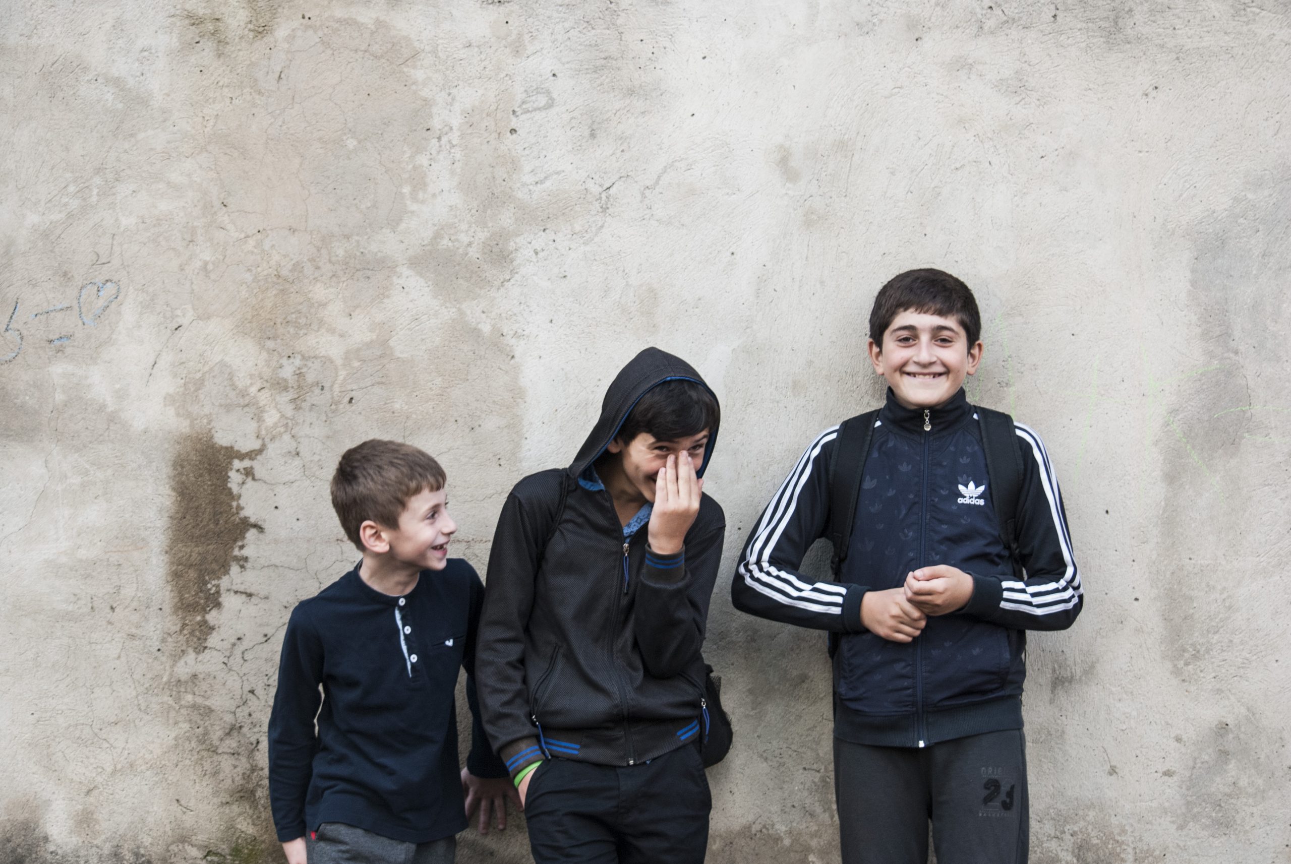 3 enfants contre un mur délabré en train de rire