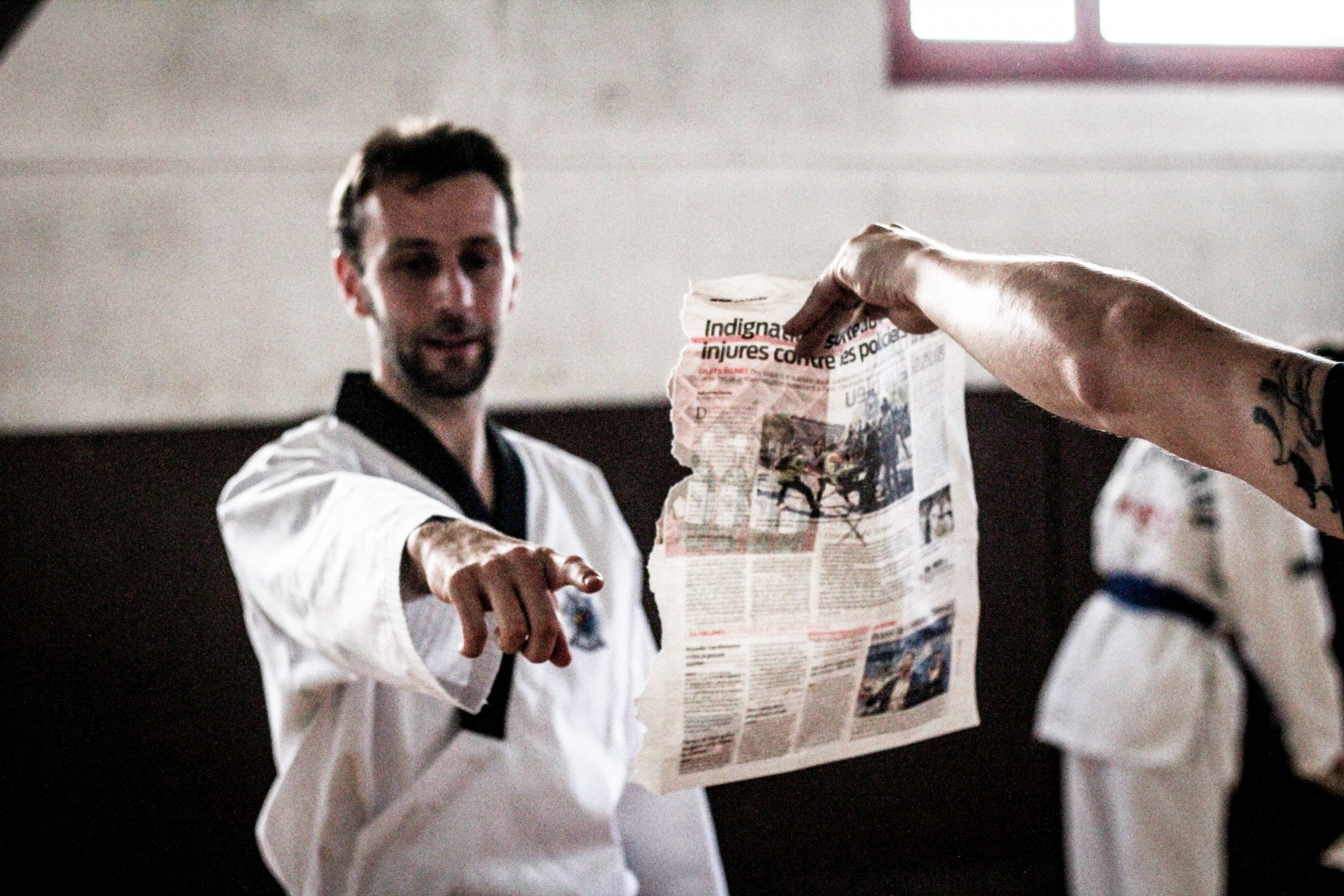 Un professeur de taekwondo montre une feuille de journal du doigt lors d'un coaching privé